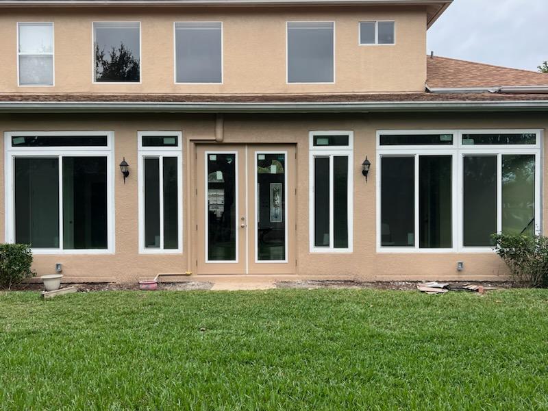 Wide view of replacement windows and exterior doors installed across a Florida home's rear elevation